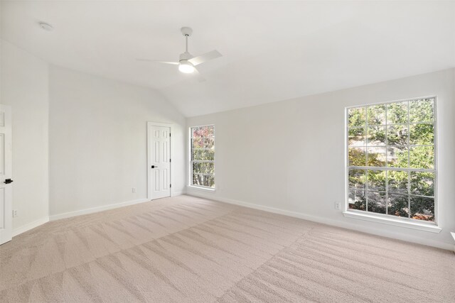 empty room with plenty of natural light, ceiling fan, light colored carpet, and lofted ceiling