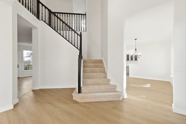 staircase with hardwood / wood-style flooring and an inviting chandelier