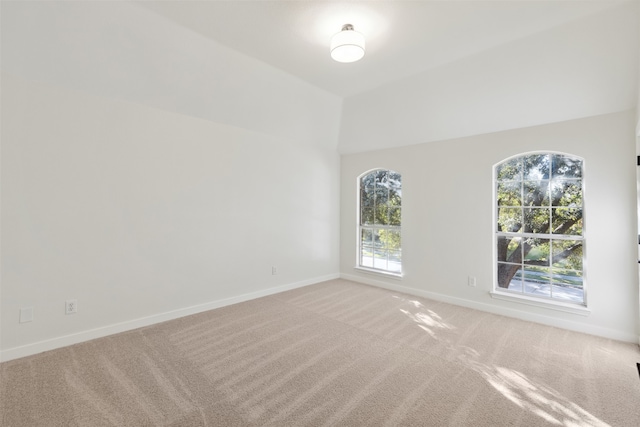 carpeted spare room with lofted ceiling