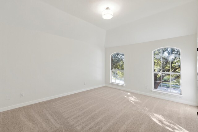 carpeted spare room with lofted ceiling