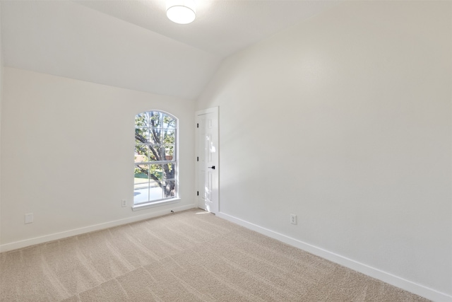 unfurnished room featuring light carpet and lofted ceiling