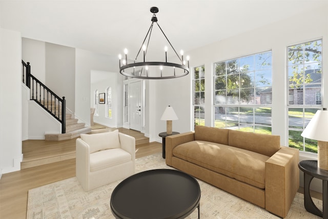 living room with light hardwood / wood-style flooring, a healthy amount of sunlight, and a notable chandelier