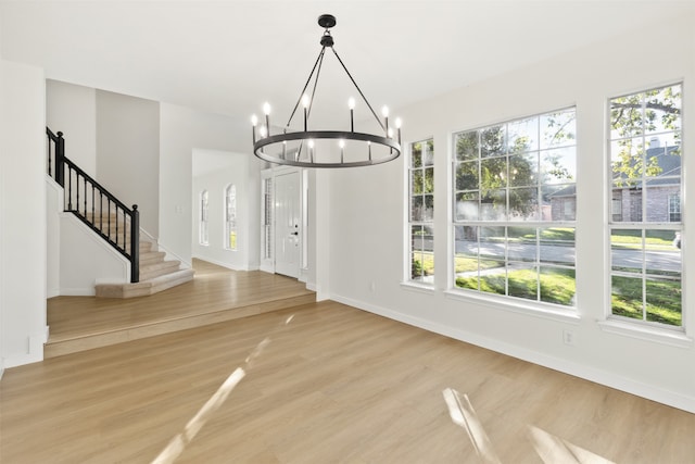 unfurnished dining area featuring a chandelier and hardwood / wood-style floors