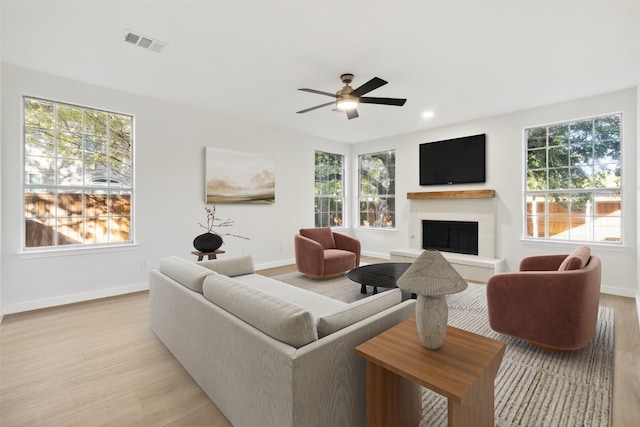 living room with ceiling fan, light wood-type flooring, and a wealth of natural light