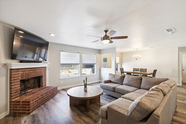 living room featuring a textured ceiling, a fireplace, ceiling fan with notable chandelier, and dark hardwood / wood-style floors