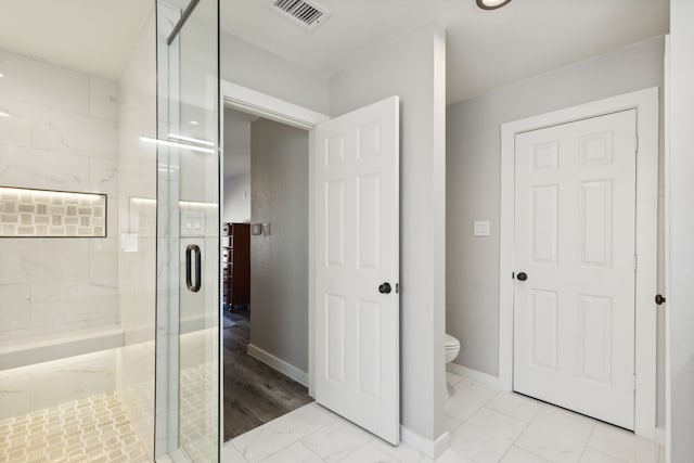 bathroom with a shower with shower door and toilet