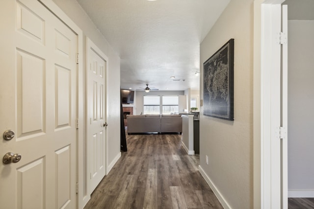 corridor with a textured ceiling and dark hardwood / wood-style flooring