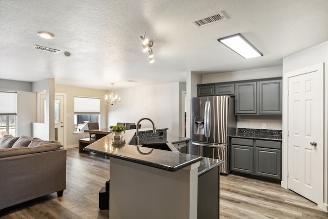 kitchen featuring stainless steel fridge, sink, an island with sink, and hardwood / wood-style flooring