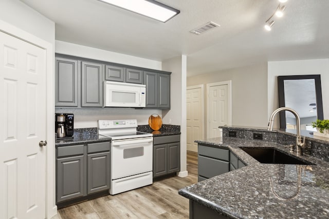 kitchen with sink, light hardwood / wood-style flooring, dark stone countertops, white appliances, and gray cabinets