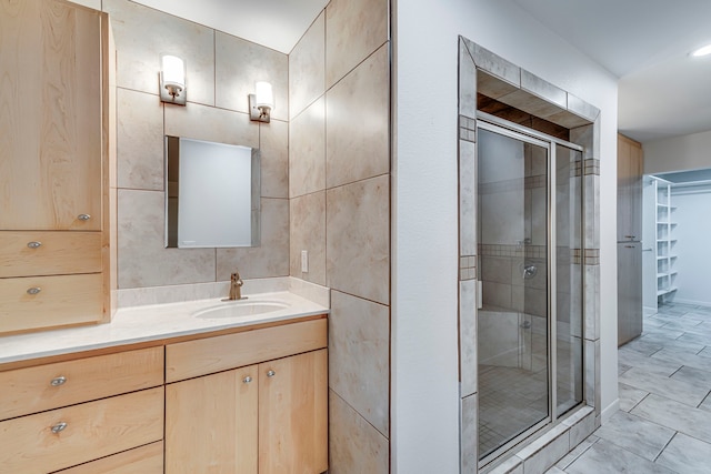 bathroom with vanity, tile patterned floors, a shower with door, and tile walls