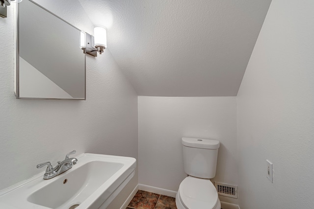 bathroom with sink, lofted ceiling, and toilet