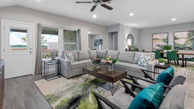 living room with ceiling fan, light wood-type flooring, and vaulted ceiling