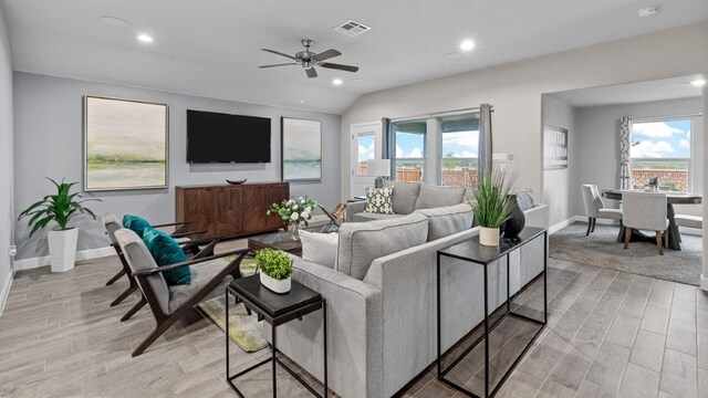 living room featuring ceiling fan, light hardwood / wood-style floors, and lofted ceiling