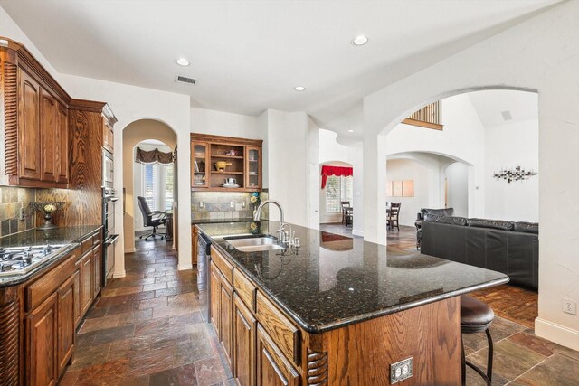 kitchen with tasteful backsplash, a kitchen island with sink, sink, and stainless steel appliances