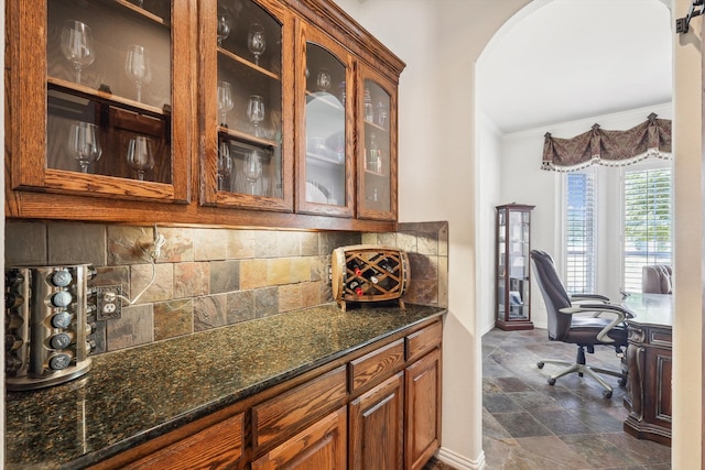 bar with ornamental molding, dark stone counters, and tasteful backsplash