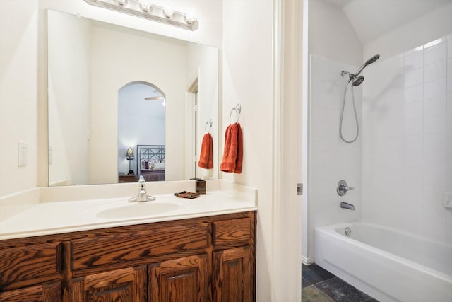 bathroom with vanity, vaulted ceiling, and tiled shower / bath