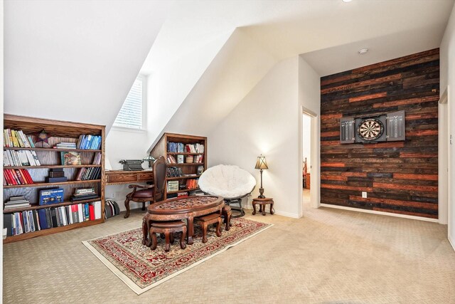 living area with wood walls, light colored carpet, and vaulted ceiling