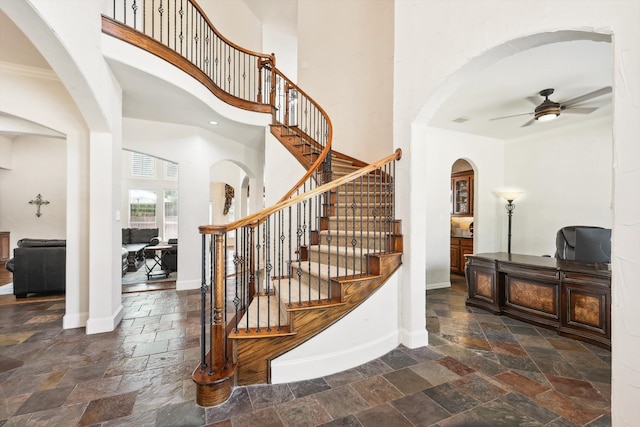 entryway with ceiling fan, crown molding, and a towering ceiling