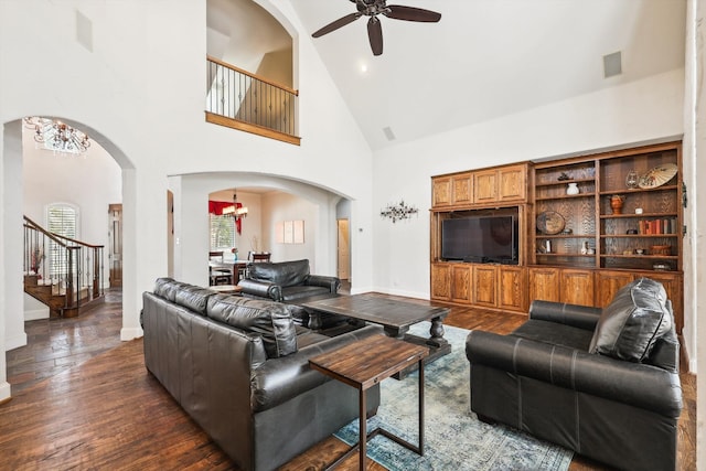 living room with ceiling fan with notable chandelier, dark hardwood / wood-style flooring, and high vaulted ceiling