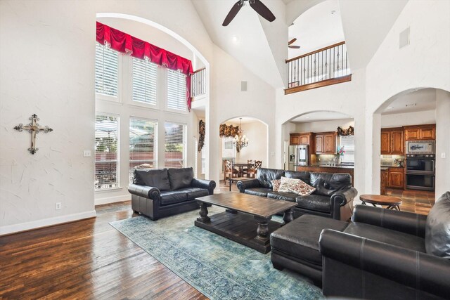 living room featuring a high ceiling, ceiling fan with notable chandelier, and hardwood / wood-style flooring