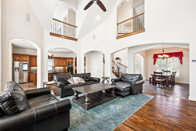 living room featuring wood-type flooring, ceiling fan with notable chandelier, and high vaulted ceiling