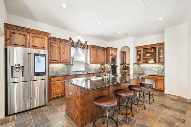 kitchen with tasteful backsplash, stainless steel appliances, sink, a center island with sink, and a breakfast bar area