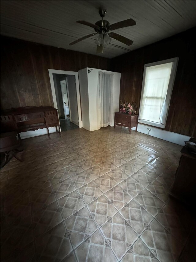 unfurnished room featuring wooden walls and ceiling fan