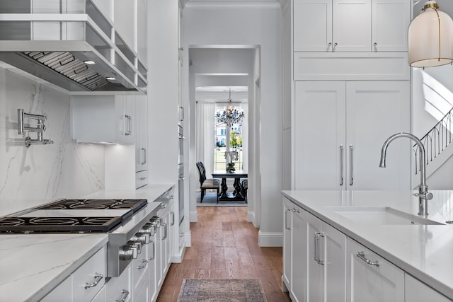 kitchen with light stone countertops, sink, wall chimney exhaust hood, dark hardwood / wood-style flooring, and white cabinets