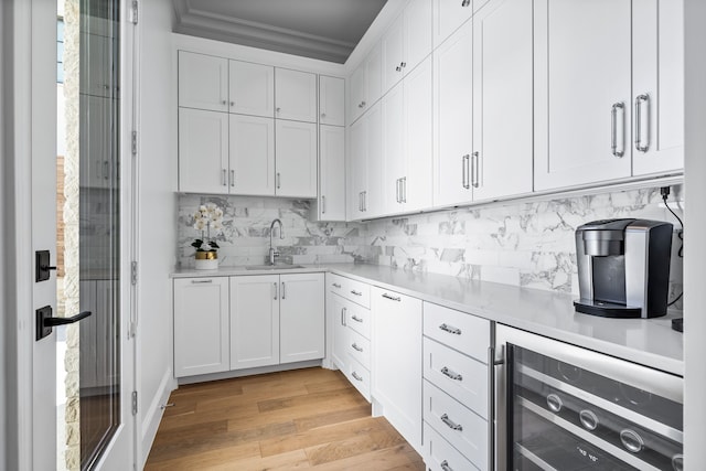 kitchen with sink, white cabinets, beverage cooler, and light hardwood / wood-style floors