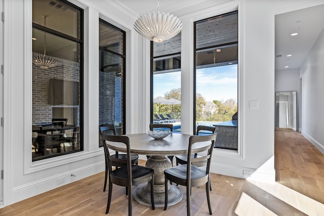 dining room featuring light wood-type flooring, an inviting chandelier, and crown molding