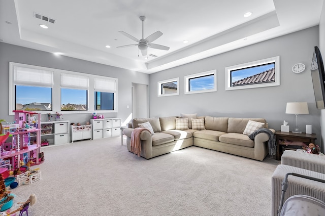 carpeted living room featuring a tray ceiling, a wealth of natural light, and ceiling fan