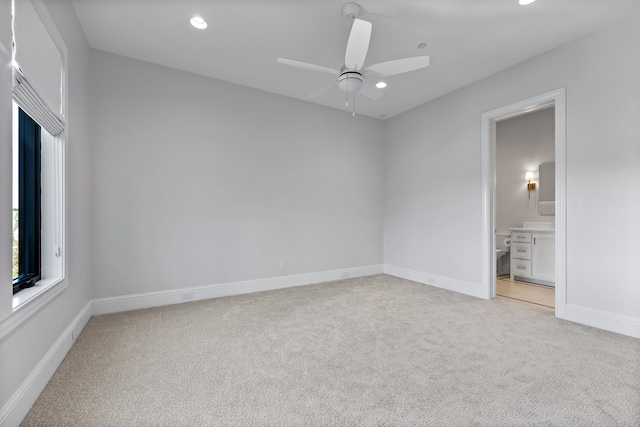 unfurnished bedroom with ensuite bathroom, ceiling fan, and light carpet