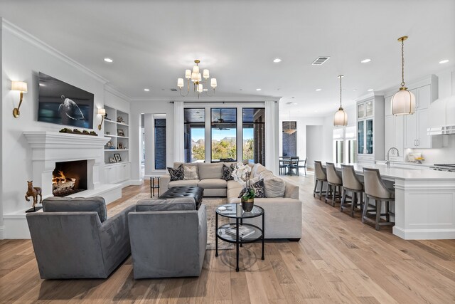 living room with built in features, ornamental molding, light hardwood / wood-style flooring, and a healthy amount of sunlight