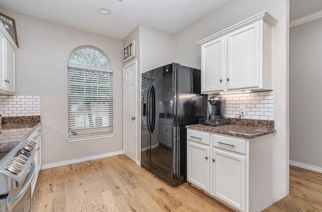 kitchen featuring white cabinetry, stainless steel range oven, and black refrigerator with ice dispenser