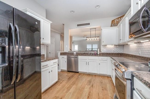 kitchen with white cabinetry, hanging light fixtures, stainless steel appliances, and light wood-type flooring