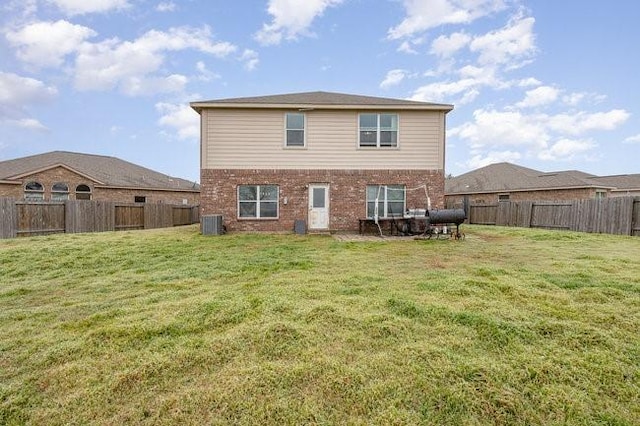 rear view of house with central AC and a lawn