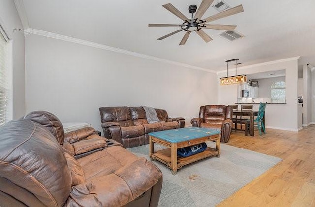 living room featuring crown molding, ceiling fan, and light wood-type flooring