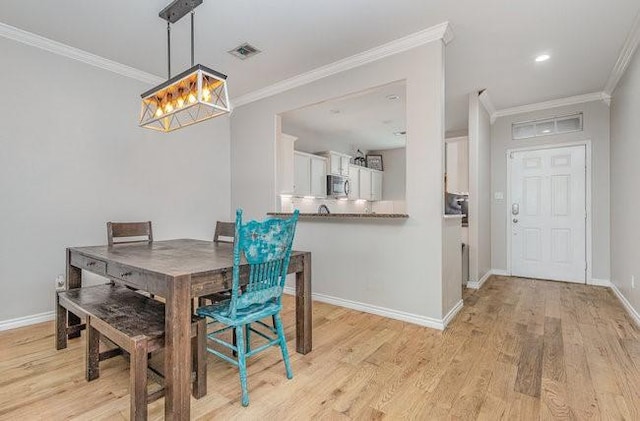 dining room with crown molding and light hardwood / wood-style floors