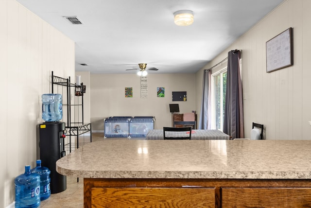 kitchen with ceiling fan and wooden walls