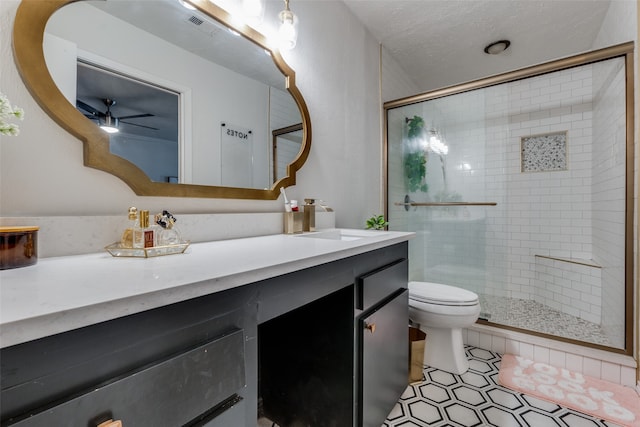 bathroom featuring a textured ceiling, vanity, a shower with door, ceiling fan, and toilet