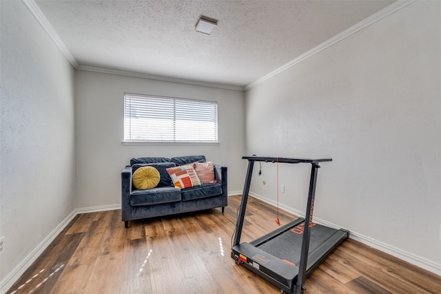 exercise area with a textured ceiling, hardwood / wood-style flooring, and crown molding