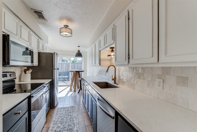 kitchen with sink, hanging light fixtures, stainless steel appliances, light hardwood / wood-style floors, and white cabinets