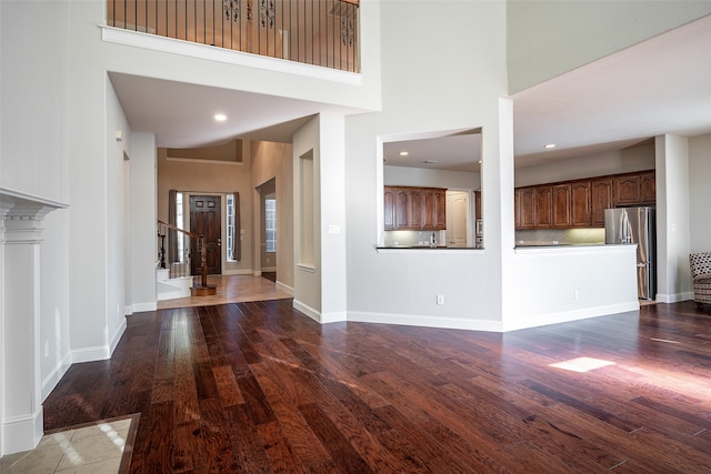 unfurnished living room with a towering ceiling and dark wood-type flooring