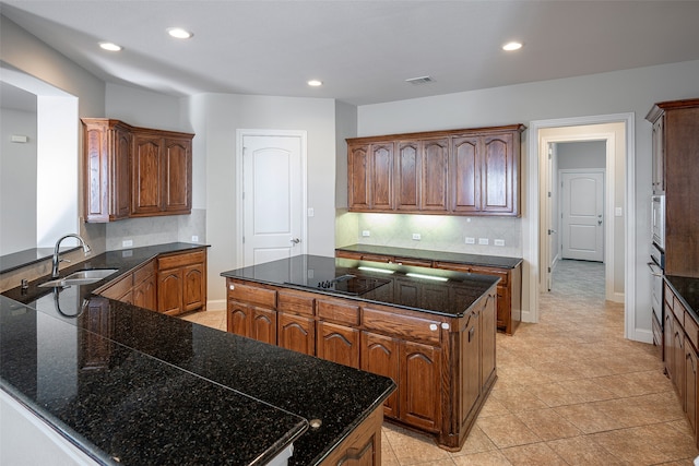 kitchen with decorative backsplash, stainless steel oven, sink, light tile patterned floors, and a center island