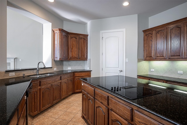 kitchen with decorative backsplash, black electric cooktop, dark stone countertops, and sink