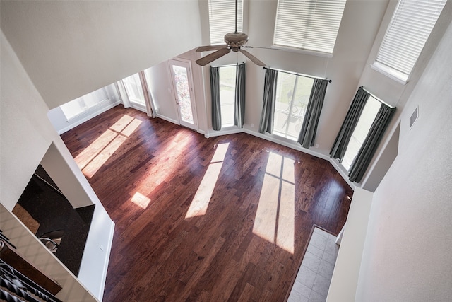 unfurnished living room featuring a high ceiling, dark wood-type flooring, and a healthy amount of sunlight