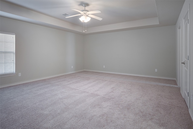 carpeted spare room featuring ceiling fan and a tray ceiling