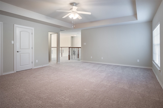 spare room with carpet floors, a tray ceiling, and ceiling fan