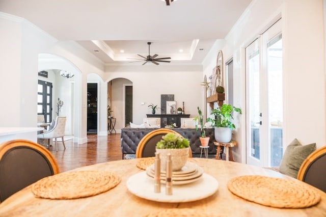 dining area featuring a tray ceiling, dark hardwood / wood-style floors, ornamental molding, and ceiling fan