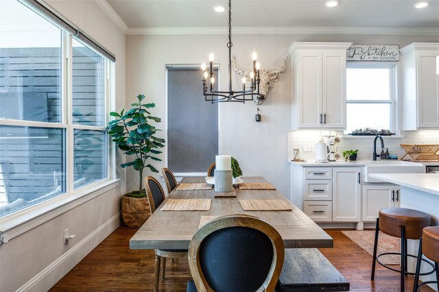 dining space featuring a chandelier, a healthy amount of sunlight, ornamental molding, and dark wood-type flooring